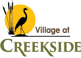 A logo with a bird and the words "Village at CREEKSIDE" in front of a yellow circle.